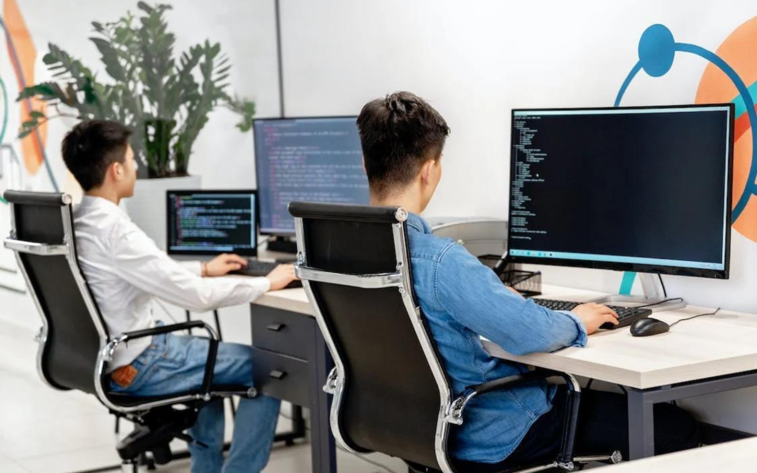 If you hire a software tester, your set up could be like these two software testers at a desk helping to secure your systems.