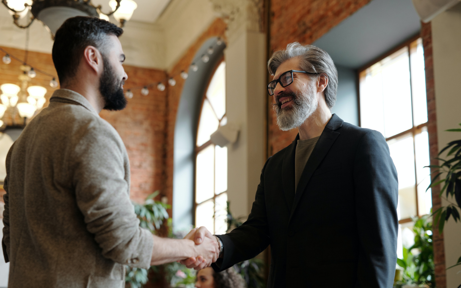 Two happy managers shaking hands because they have successfully managed to retain tech talent