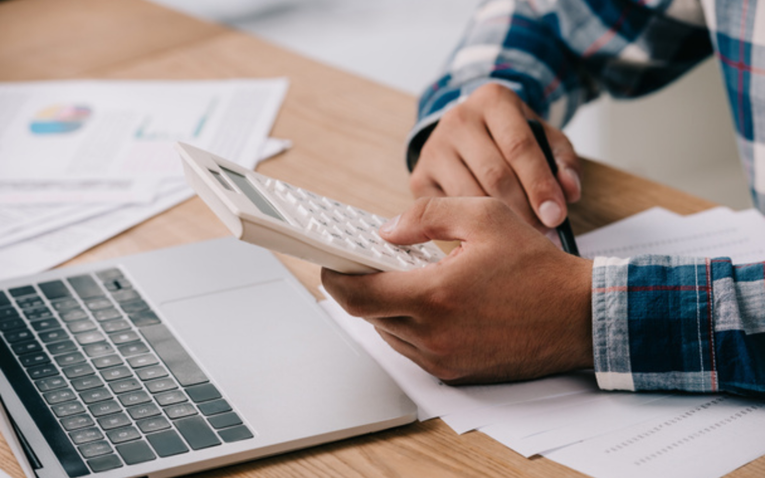 Person working out how changes to IR35 will impact them on a calculator surrounded by papers.