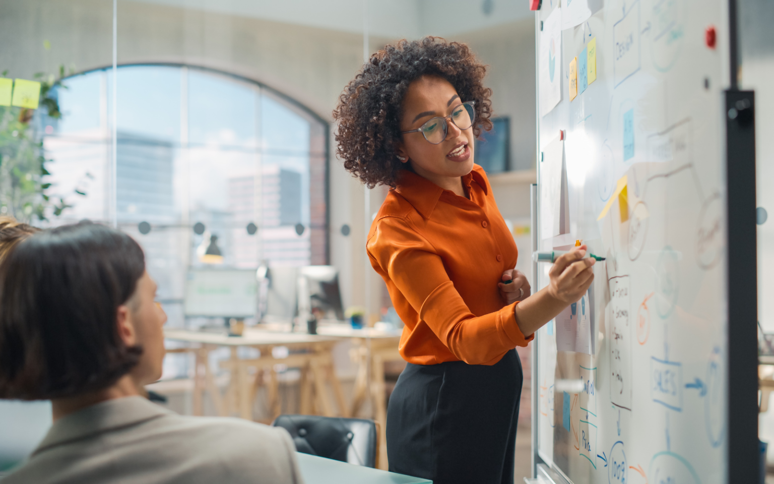 Woman writing the business' tech hiring challenges on the board